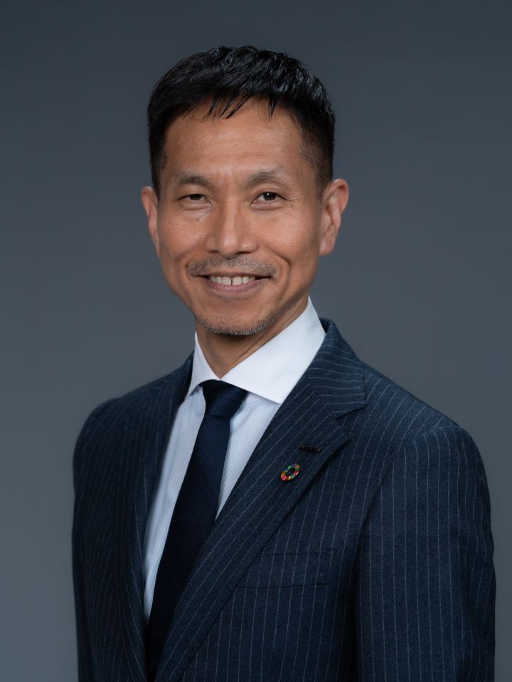 Portrait of Toru Ihara with navy blue suit, tie and NISSAN corporate pin, SDGs badge (smiling)