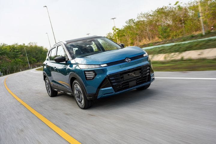 Blue Nissan KICKS e‑POWER driving on a curved road surrounded by greenery.