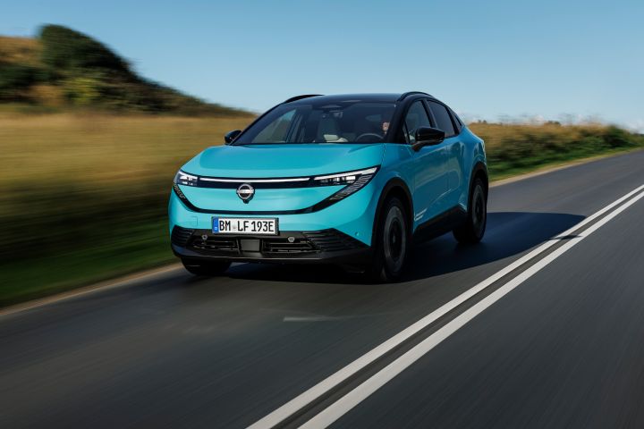 3/4 Frontaufnahme eines türkisen Nissan LEAF, der über eine dänische Landstraße fährt, im Hintergrund ist ein gelbgoldenes Feld unscharf zu erkennen