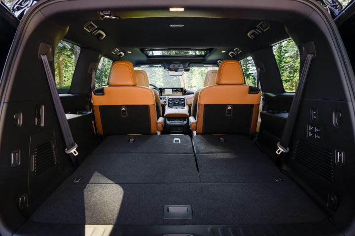 View of the interior from the open hatch back of a 2025 Nissan Armada, the black felted cargo space and rear seats can be seen.