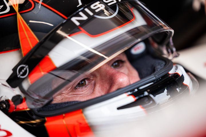 Norman Nato sitzt mit aufgesetztem Helm und hochgeklapptem Visier im Nissan Formel E Rennwagen mit der Nummer 23 in der Teamgarage.