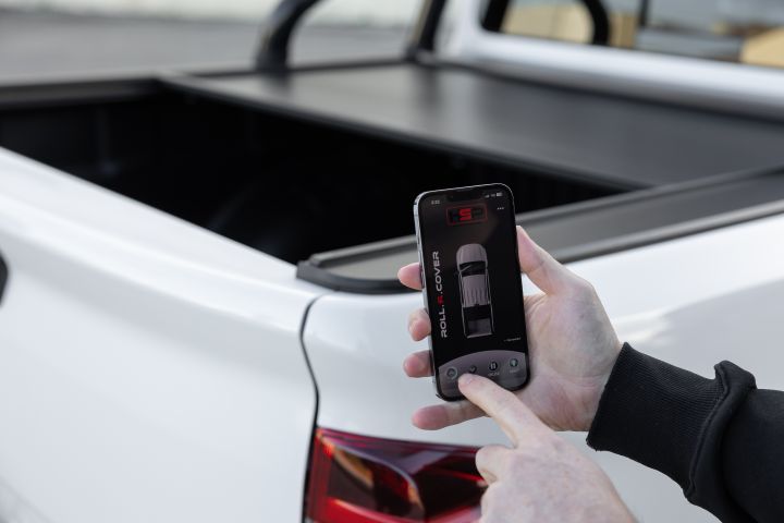 Man using his phone to close an electronic, app-operated tailgate cover