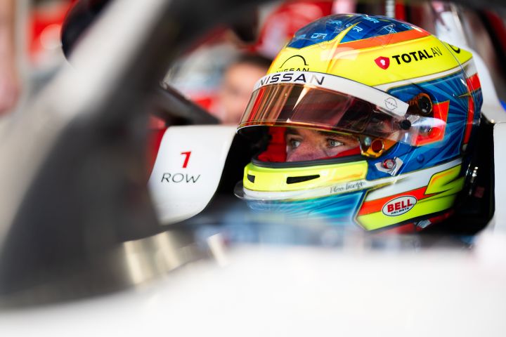 Oliver Rowland sitzt mit Helm im Auto in der Garage des Nissan Formula E Teams