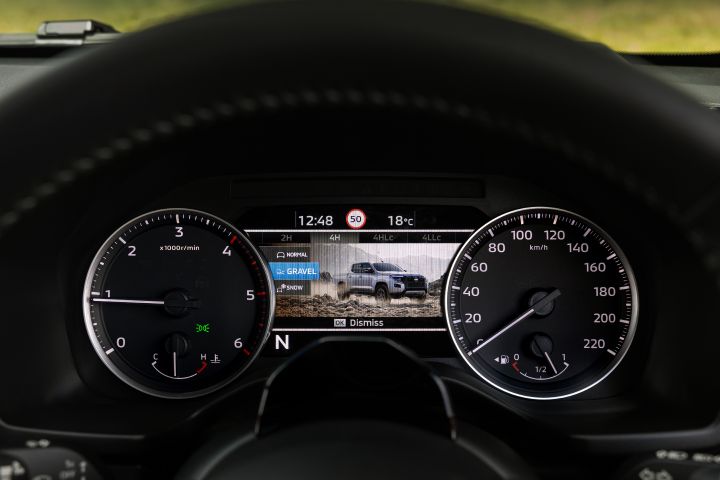 2026 Nissan Navara PRO-4X finished in Boulder Grey showing the terrain-program display with GRAVEL selected and dusty-road imagery.