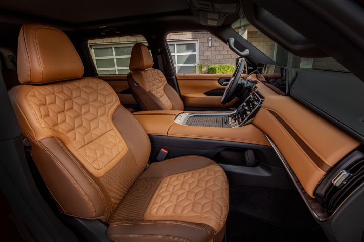 The two tone tan front seats, dashboard, and center console all viewed from the passenger door of the 2025 Nissan Armada.