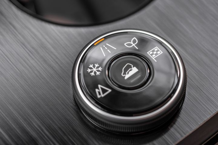 Close up of a circular mode dial with snow, road, mountain, eco, and flag icons, inside the 2025 Nissan Rogue rock creek.
