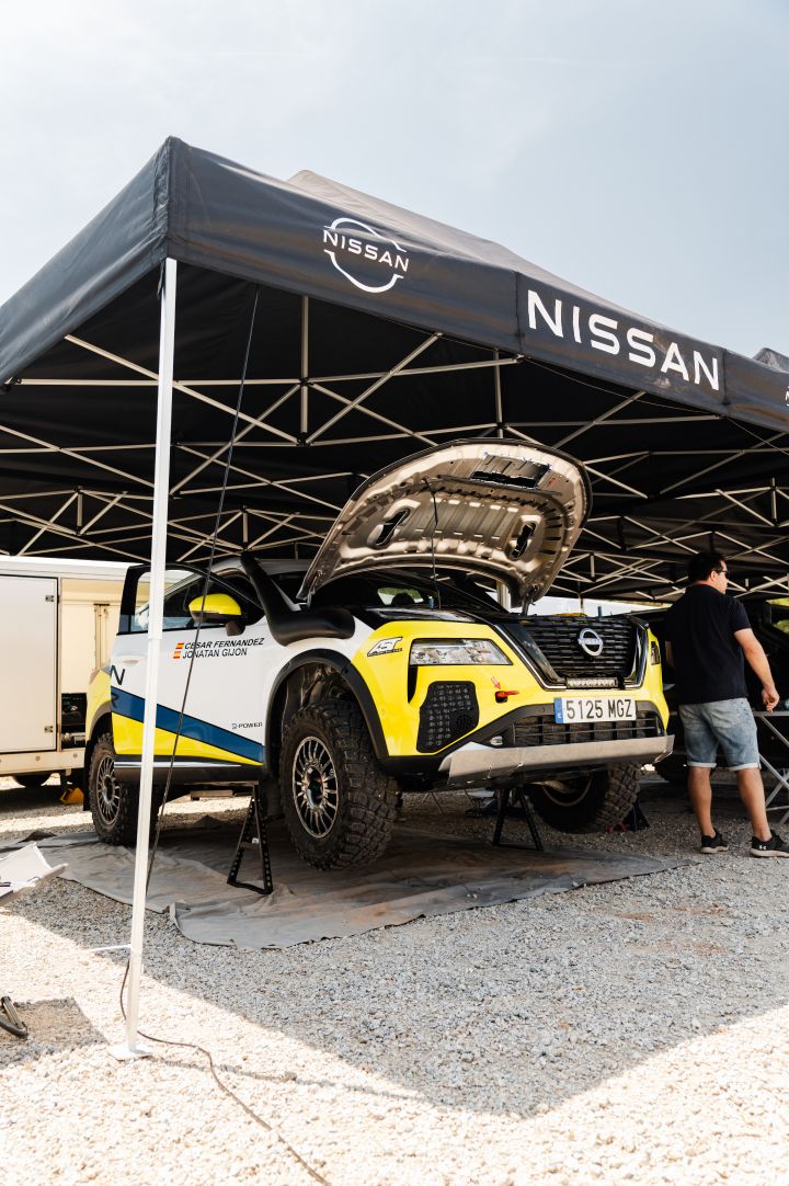 Der Nissan X‑Trail Rennwagen für die Baja Aragon Rallye 2024 steht aufgebockt und mit geöffneter Motorhaube im Nissan Pavillon
