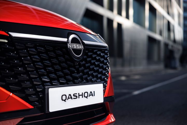 Gros plan de ¾ de la calandre du Nissan Qashqai rouge Fuji