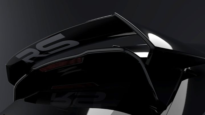 A close-up shot of a large black rear wing with glossy finish, featuring white lettering that reads 'RS.' The image emphasizes the aerodynamic shape and reflective surface of the wing. The background is a dark gray, highlighting the wing's contours and details.