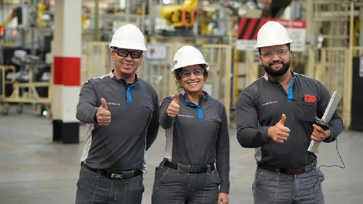 Três funcionários da fábrica nissan no México olhando para a câmera com braços cruzados e sorrindo