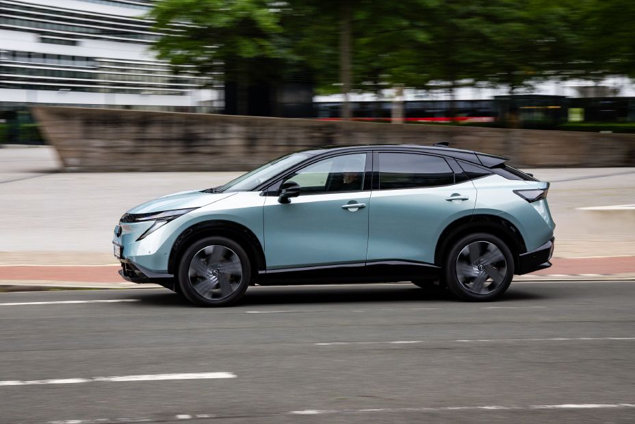Seitliche Fahraufnahme eines hellblauen Nissan Ariya in städtischem Umfeld