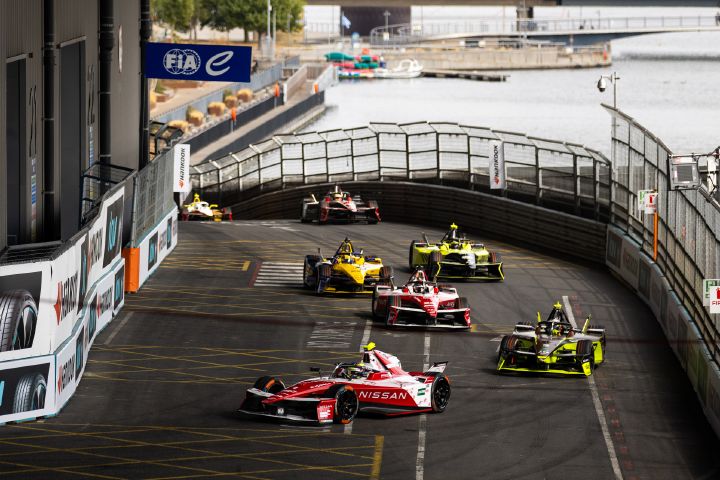 Oliver Rowland auf der Rennstrecke im Nissan e‑4ORCE 05 mit der Startnummer 1 während des London E-Prix, hinter ihm mehrere andere Fahrzeuge und im Hintergrund die Themse.