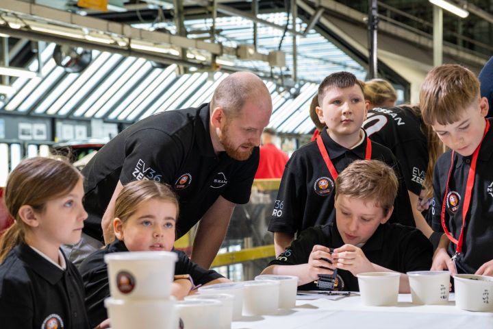 A Nissan employee explaining the Nissan Skills Foundation LEGO activity to school children.