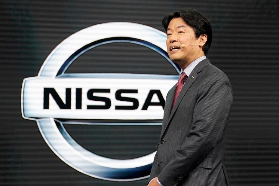 Un homme sur scène lors de la conférence de presse du Salon automobile de Tokyo avec le logo Nissan derrière lui