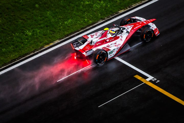 Luftaufnahme von Oliver Rowland auf der Rennstrecke im Auto mit der Startnummer 1, wobei Spritzwasser aus dem Heck des Wagens aufsteigt.