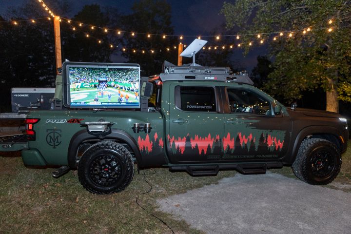 The 2025 Nissan Frontier Trailgater edition parked outside under glowing string lights at night time.