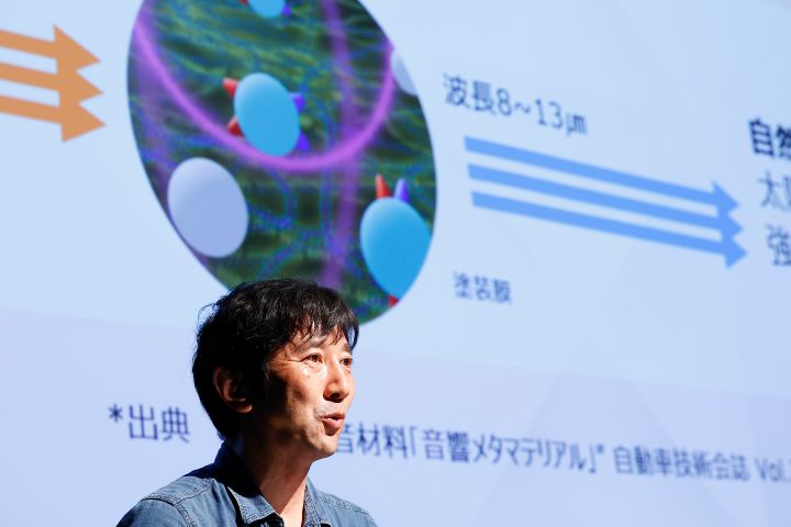 男性がディスプレイの前に立っており、技術的な内容を聴衆の前でプレゼンテーション形式で説明している様子