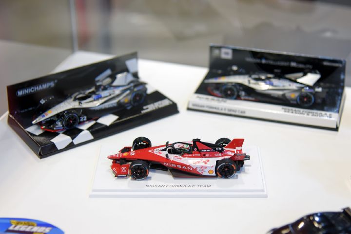 Miniatura de carro da equipe Nissan de Fórmula E com outros dois carrinhos de corrida ao fundo