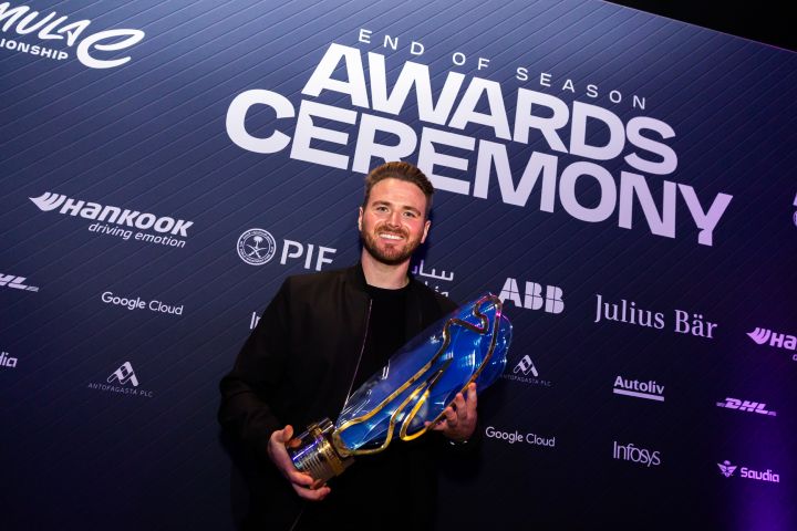 Oliver Rowland lächelt bei der „End of Season Awards Ceremony” mit der Trophäe für die Fahrer-Weltmeisterschaft in seinen Händen.