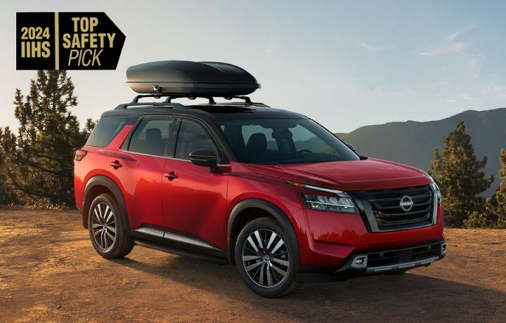 Estacionada en Medio de la naturaleza una Nissan Pathfinder Roja accesorizada con el logo 2024 IHSS TOP SAFETY PICK