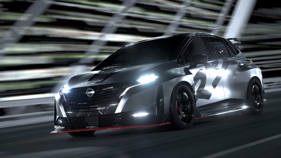 Ein silber-schwarz zweifarbiger Sportwagen, der Aura Nismo RS Concept, fährt mit hoher Geschwindigkeit über eine Brücke. Das Fahrzeug ist nach links vorne geneigt, die hellen Scheinwerfer leuchten.