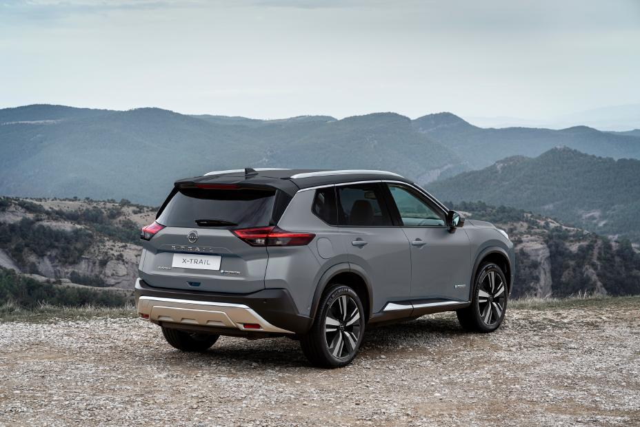 Parte trasera de SUV Nissan estacionado en una explanada de tierra con montes de fondo