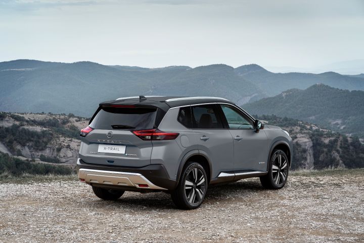 Parte trasera de SUV Nissan estacionado en una explanada de tierra con montes de fondo