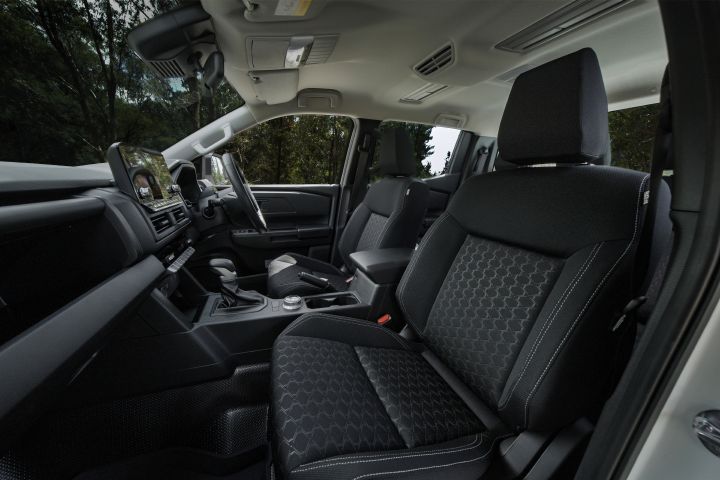 2026 Nissan Navara SL dual cab ute finished in Alpine White shown from the passenger-side interior angle, featuring the front seats, cloth trim, centre console and cabin roof lining.