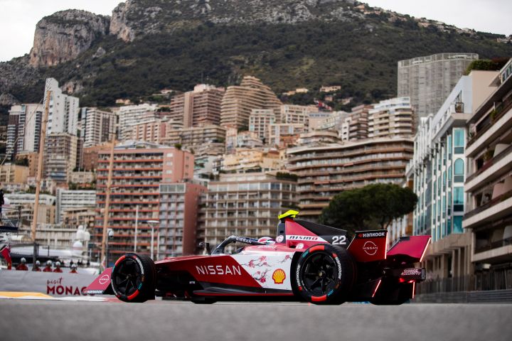 Oliver Rowland on track in Monaco, with buildings and mountains in the background