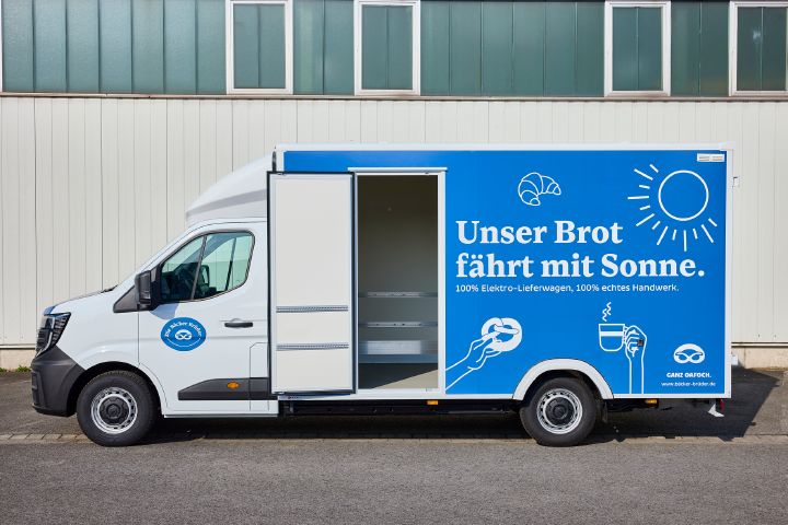 Seitenansicht des Nissan Interstar-e mit blau beklebtem Bäckereikoffer mit dem Schriftzug "Unser Brot fährt mit Sonne" und geöffneter Seitentüre