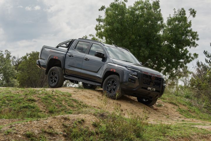 2026 Nissan Navara PRO-4X finished in Boulder Grey paused rear three‑quarter on a sandy rise with embossed tailgate and tall tail‑lamps.