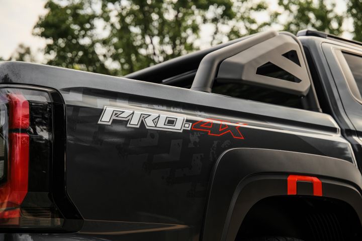 2026 Nissan Navara PRO-4X finished in Boulder Grey showing the rear tub side with PRO-4X decal, sports bar, tail-light edge and red-accented fender flare.