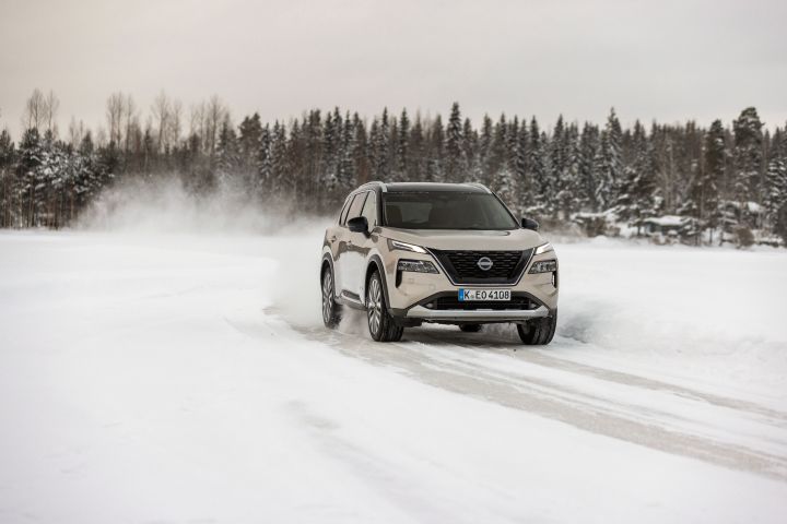 X‑Trail e‑4ORCE driving on the frozen lake with snow and trees in the background (front shot)