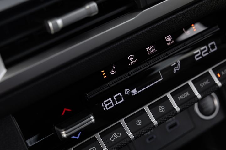 Close-up of the dual-zone climate-control panel in a 2026 Nissan Navara ST-X, showing temperature settings, heated-seat indicators, airflow controls, and front and rear demister buttons.