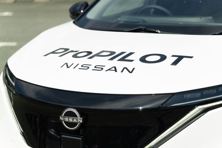 Frontpartie eines weißen Nissan Ariya, auf der Motorhaube ist der schwarze Schriftzug „PROPILOT NISSAN” zu erkennen.