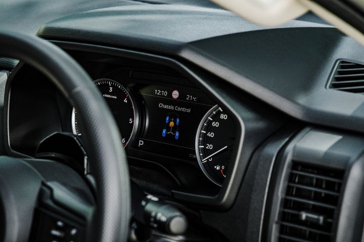 2026 Nissan Navara SL dual cab ute finished in Alpine White with a close-up of the instrument cluster, showing analogue gauges and the central chassis control display.