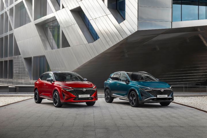 Twee Nissans Qashqai naast elkaar geparkeerd bij de ingang van een modern gebouw
