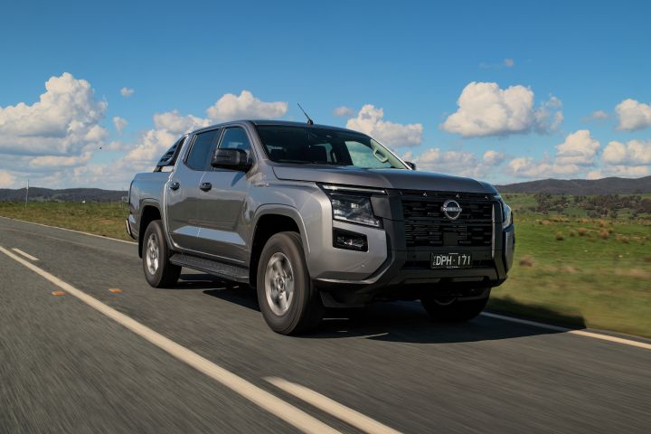 2026 Nissan Navara ST dual cab ute finished in Summit Silver captured driving from a front three-quarter angle on a country road with open farmland.