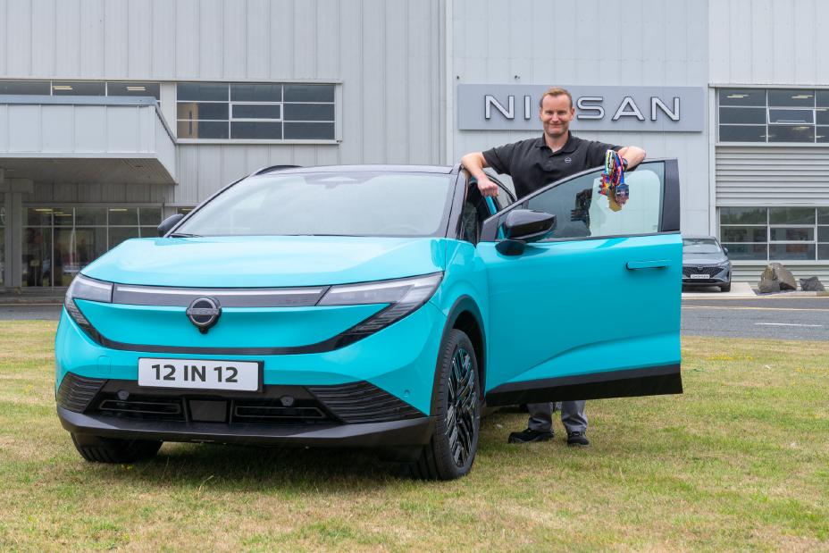 Nissan Engineering General Manager, Guy Reid, standing next to the New Nissan LEAF and holding up his Marathon medals