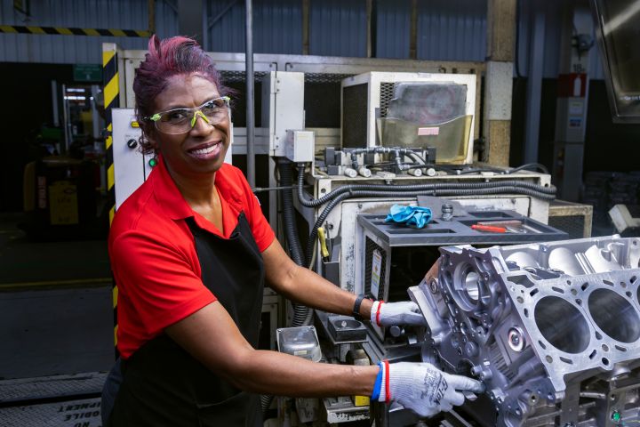 Image of a manufacturing team member holding on to a machine part