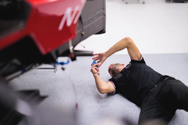 Ein Mechaniker liegt auf dem Rücken auf dem Boden und fotografiert ein Nissan Formel E Rennfahrzeug von unten
