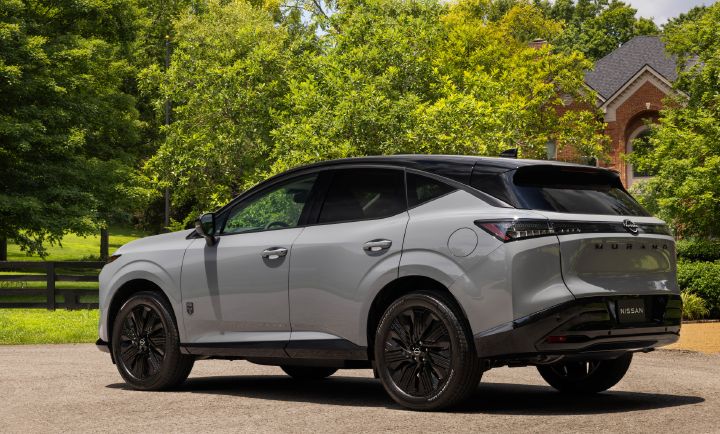 Rear angled view of the 2027 Nissan Murano Dark Armor with trees and a house behind.