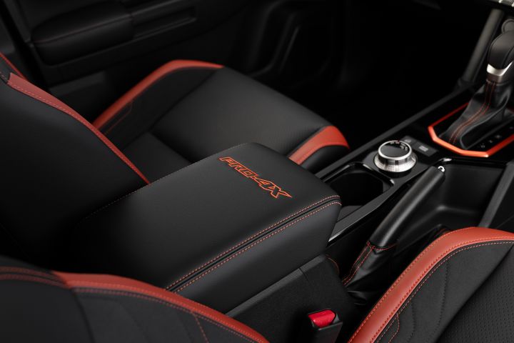 2026 Nissan Navara PRO-4X finished in Boulder Grey highlighting the centre console with embroidered armrest, drive-mode dial, cupholders and red-trimmed shifter surround.