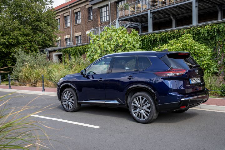 Blick von schräg hinten auf einen parkenden, dunkelblauen Nissan X‑Trail