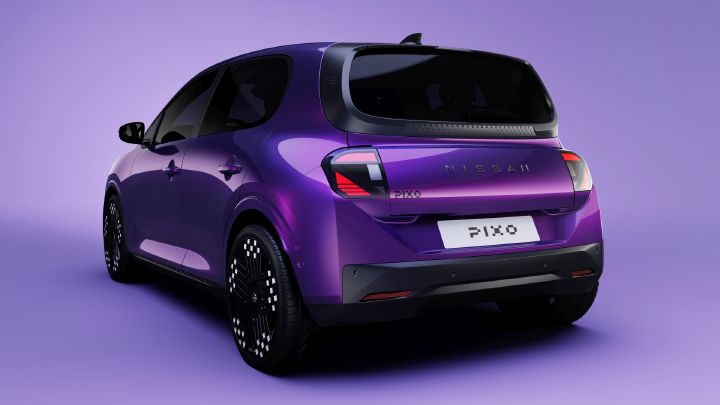Photograph of a purple Nissan Pixo electric hatchback shown from rear three-quarter view against a lavender background. Sleek black windows, patterned wheels, angular taillights, rear spoiler, and illuminated-looking “NISSAN” and “PIXO” labels define vehicle design.