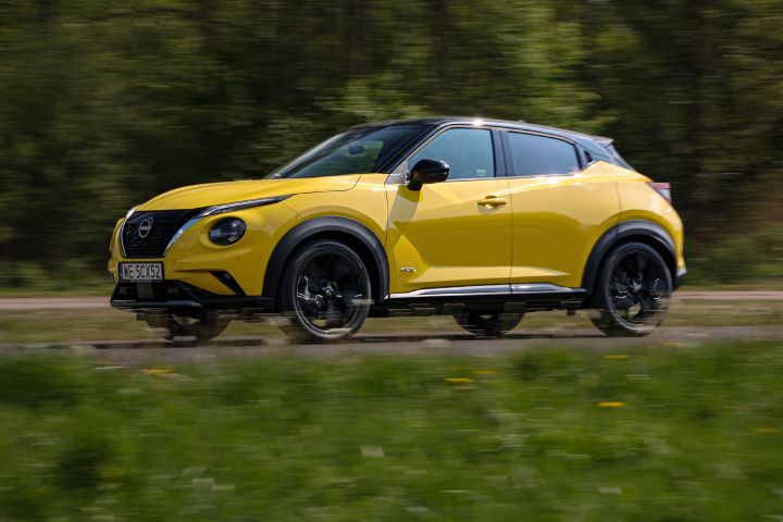 Jadący żółty Nissan Juke (widok z boku) na tle zieleni