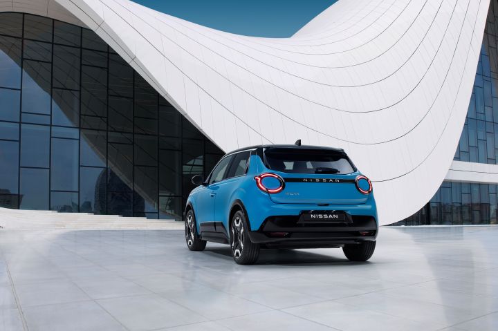 hero shot - rear 7/8 view of new Micra in blue gear color in front of a white & blue design architectural building