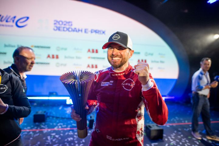 Uśmiechnięty Oliver Rowland z trofeum Jeddah E-Prix w prawej dłoni