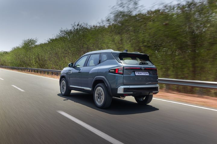 Nissan Tekton travelling on an open road, viewed from the rear three-quarter angle.