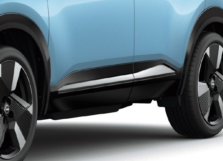 Close-up of the lower side of a bluish Nissan Kicks. The vehicle faces right, highlighting the door sculpting and lower body design.
